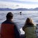 A whale’s tail breaches the water as a family watches from a boat