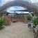 A reed arch leading to a sitting area on a sandy beach