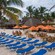 People sitting on a group of chairs next to umbrellas on Corona Beach in Progreso, Mexico