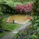 A secluded hot springs enclosed by a stone border, set amid flowering plants and trees