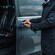 A private driver opening the door of a luxury mini bus