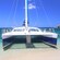 A sailing catamaran docked on the beach with other boats on the water in the distance