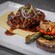 Steak served with a sauce and grilled vegetables.