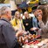 A Guest samples food while a shopkeeper and other Guests watch