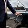 A private driver opening the door of a luxury sedan
