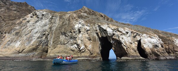 People in a tour boat near the rock tunnel at Cerro Brujo on San Cristobal Island, one of the Galapagos Islands