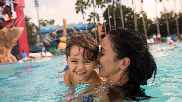 In a themed pool, a mother holds her smiling child