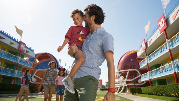 On the lawn at Disney’s All Star Sports Resort, a father holds his smiling child