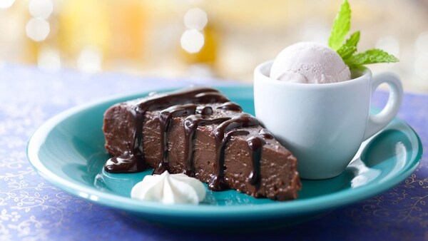 A slice of chocolate pie on a plate with a scoop of vanilla ice cream