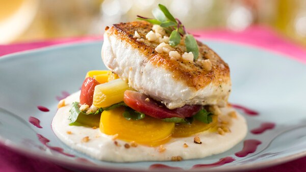 A plate of seared fish with fresh beets and greens