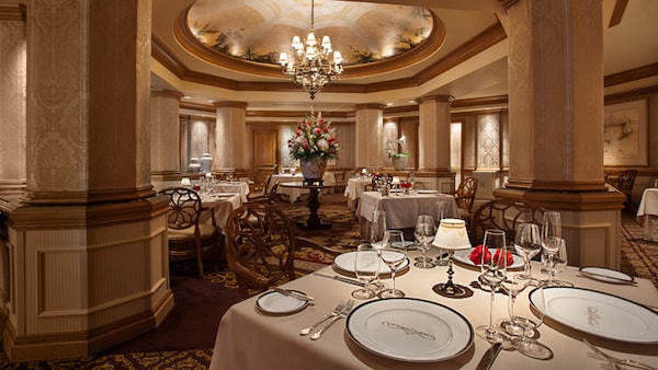 An elegant dining room with columns, a chandelier and tables at Victoria & Albert's restaurant