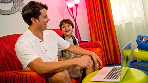 A boy and his father on a couch in a Finding Nemo Family Suite at Disney's Art of Animation Resort