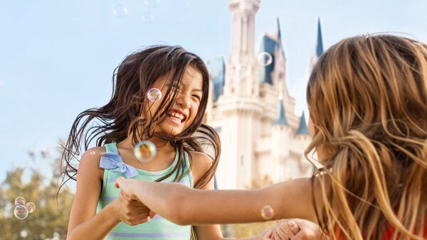 Two little girls dancing in front of Cinderella Castle at Magic Kingdom park in Florida