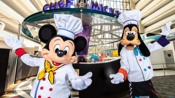 Mickey Mouse and Goofy dressed as chefs with their arms outstretched