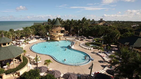Mickey-shaped pool with waterslide, surrounded by lounge chairs