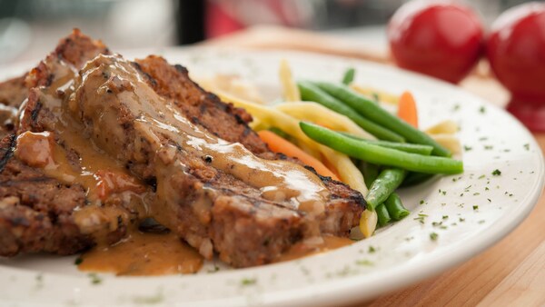 2 slices of meatloaf covered in gravy with vegetables