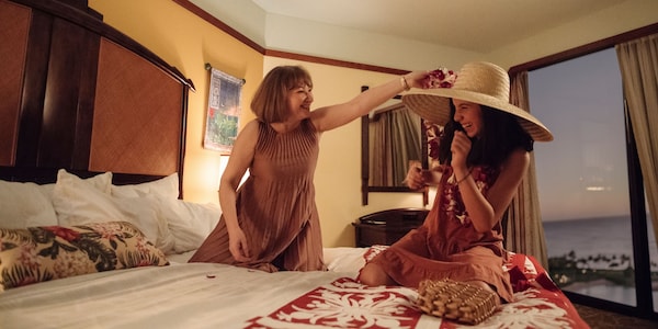 In a room at the Aulani Resort, one woman offers a Hawaiian lei to another 