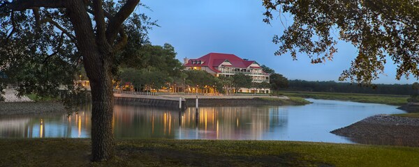 A hotel building near a large pond and trees