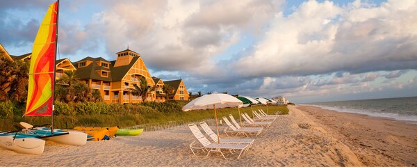 Several lounge chairs on a long beach and a hotel building