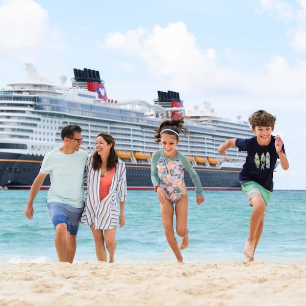 A cruise ship on the tranquil sea as a family of 4 walk along a sandy beach