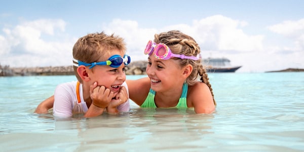 A young girl embracing a young boy as they smile and relax in the surf