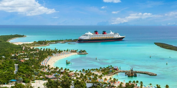 A Disney Cruise Line ship docked by a sunny Caribbean shoreline