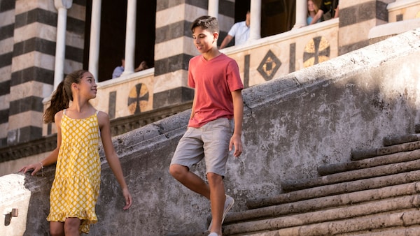 A boy and girl walk down the stone steps of a church in Piazza dei Mulini, in Positano, Italy 