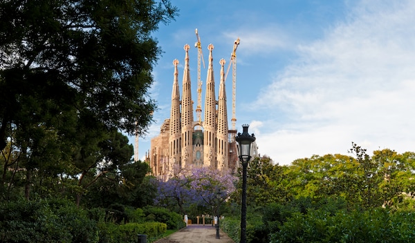 The famous Sagrada Familia church in Barcelona, Spain, surrounded by lush foliage