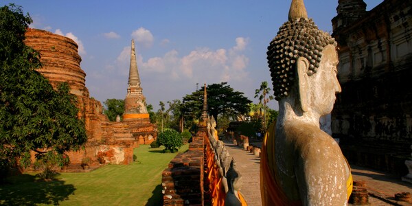 The historic Wat Yai Chai Mongkhon temple in Thailand, featuring a tall, striking pagoda and rows of Buddha statues