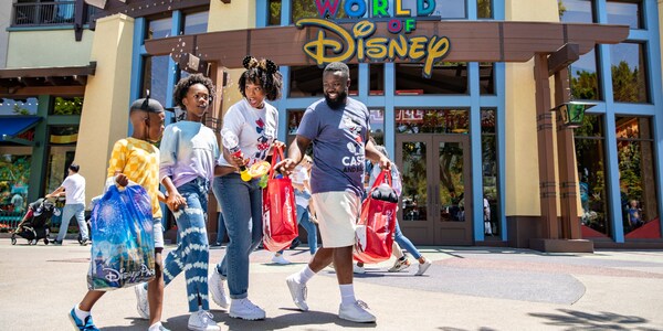 A family of 4 walks by the World of Disney store at the Disneyland Resort