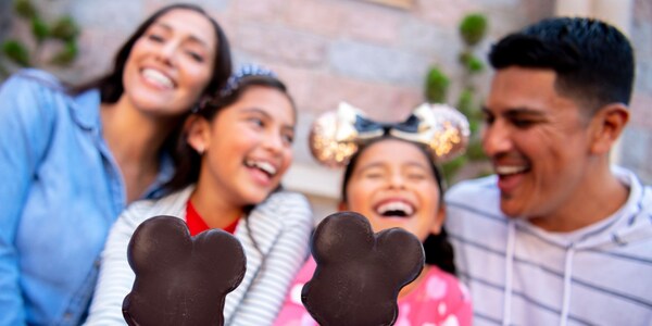 A family laughing while holding 2 Mickey Mouse shaped ice cream bars