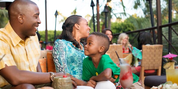 A family of 3 seated outdoors at a table at Aulani, A Disney Resort and Spa