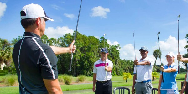 A golf pro teaching a group how to hold a golf club