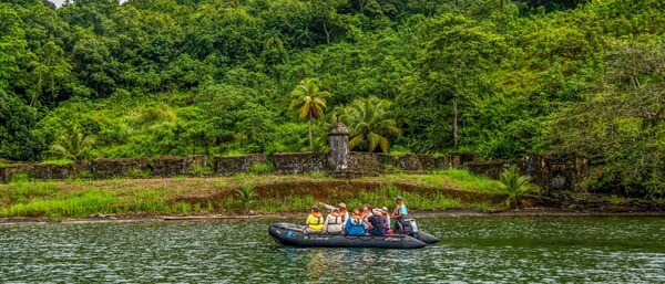 A small boat filled with people passing by lush landscapes in Central America