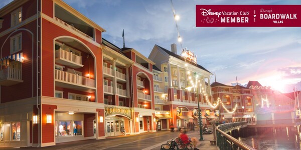 Disney’s BoardWalk Villas and the boardwalk itself, brightly lit at dusk, over which a banner reads, ‘Disney Vacation Club Member, Disney’s BoardWalk Villas’