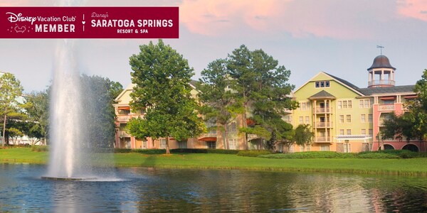 A fountain in the middle of a body of water sprays in front of Disney’s Saratoga Springs Resort and Spa, over which a banner reads, ‘Disney Vacation Club Member, Disney’s Saratoga Springs Resort and Spa’
