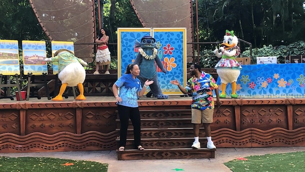 Donald Duck, Stitch, Daisy Duck and Moana perform on an outdoor stage with 2 Cast Members