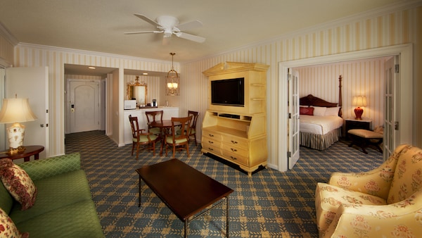 Área de estar com armário de mídia amarelo, sofá verde e poltrona floral amarela