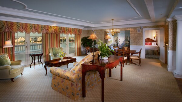 Sala de estar formal com detalhes com coroas, cortinas com saias e mobílias com inspiração Vitoriana