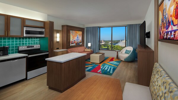Una villa en Bay Lake Tower at Disney’s Contemporary Resort, con una cocina, área de comidas y una sala de estar con un sofá, mesa ratona, silla y TV