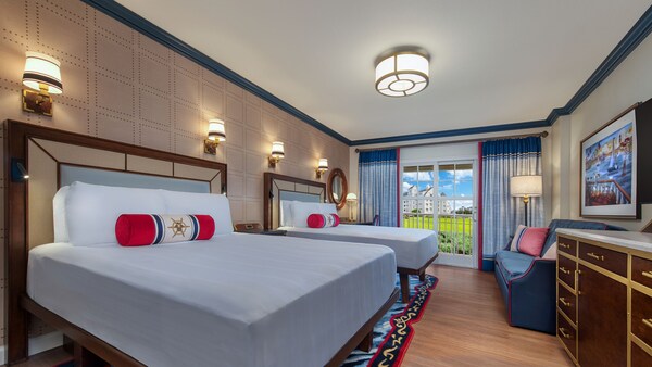Una habitación Club Level con vista de Disney's Yacht Club Resort con 2 camas, un sofá, una cómoda y terraza