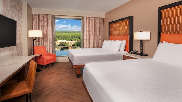 A desk, chair, TV, lamp, 2 upholstered chairs, window, coffee table and bed with side table and telephone Choosing the Perfect Moderate Resort Room Category Walt Disney World Water View Gran Destino Tower Coronado Springs