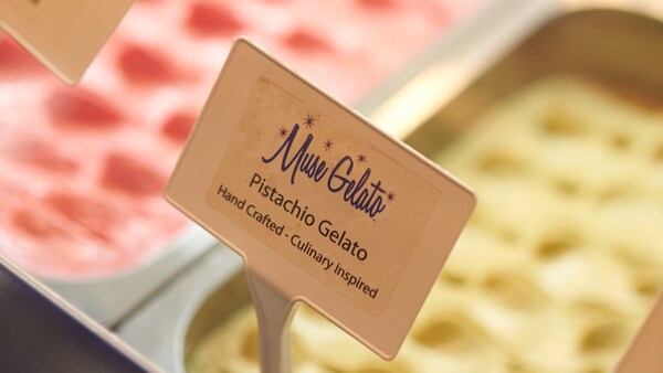 Un récipient en métal rempli de gelato dans une boîte glacée et une enseigne indiquant « Pistachio Gelato, handcrafted and culinary inspired »