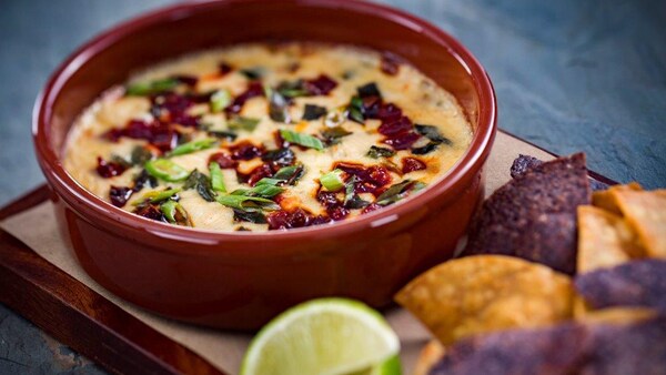 Une trempette au fromage manchego et au chorizo, servie avec tranches de citron et croustilles