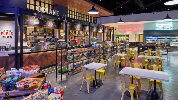 Un restaurante de servicio rápido con estaciones para pedir snacks y bebidas, y mesas con sillas para dos o cuatro personas