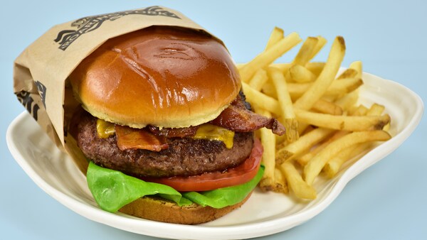 A cheeseburger with lettuce, tomato and bacon served with french fries