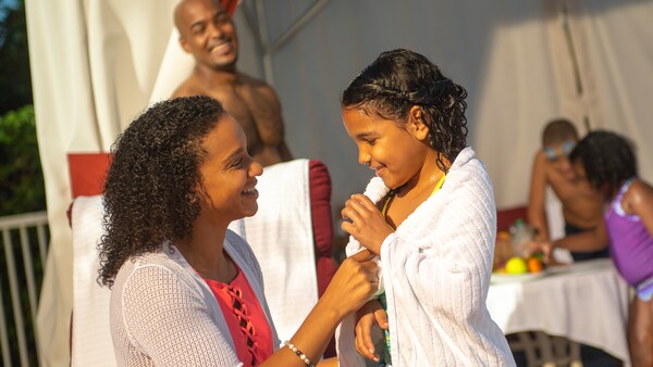 A mother wraps her daughter in a towel outside a poolside cabana