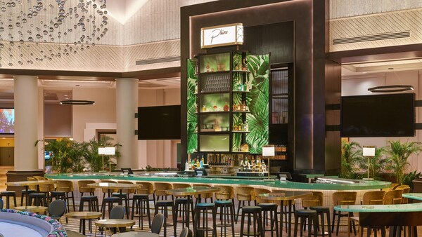 Phins lounge area, featuring a large curving bar surrounded by stools and several tables with stools nearby.