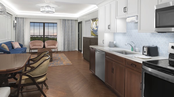 The kitchen area of a Resort suite has a sink, oven, dishwasher and a dining table