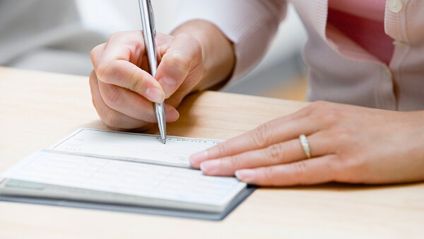 Close-up of a woman's hands writing in a checkbook